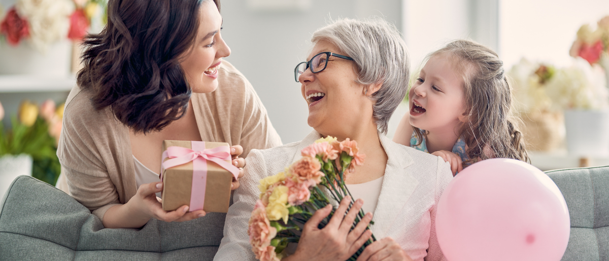 Kobiety w różnym wieku uśmiechają się do siebie wręczając najlepszy prezent na dzień mamy