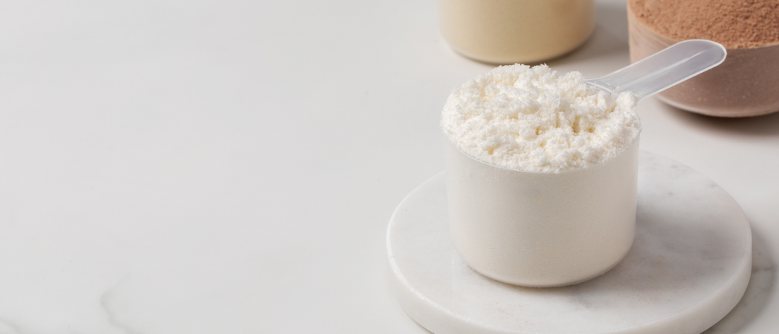 Miarka wypełniona kreatyną w proszku na jasnym marmurowym blacie