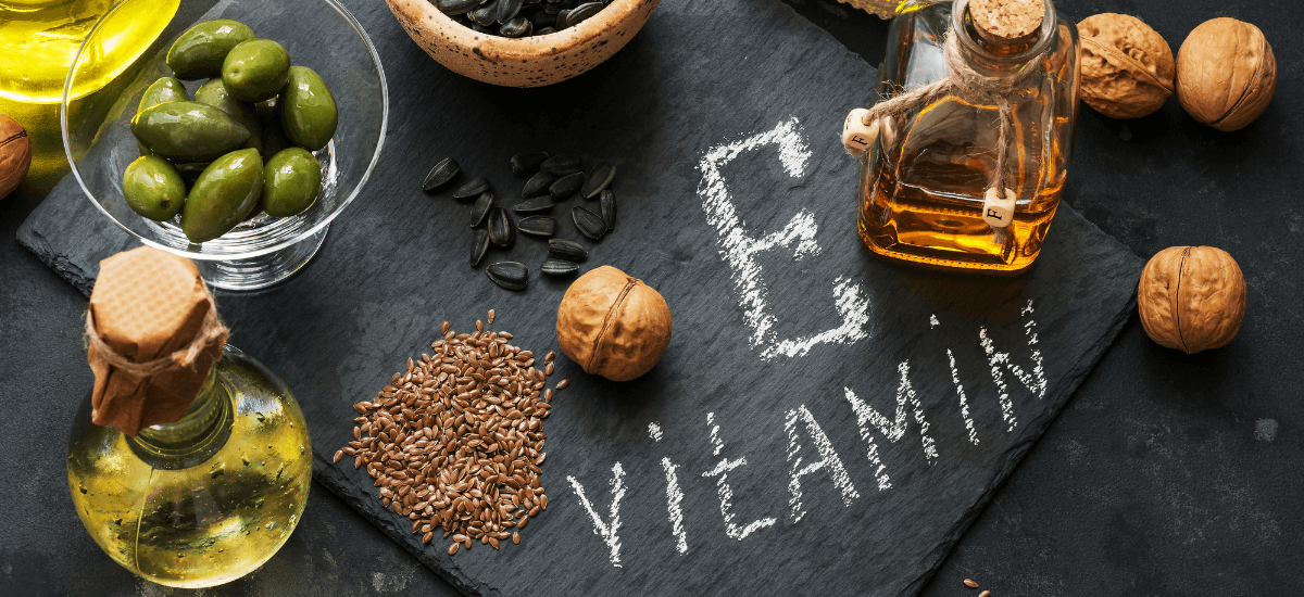 Produkty z witaminą e ułożone naokoło tablicy z napisem vitamin E