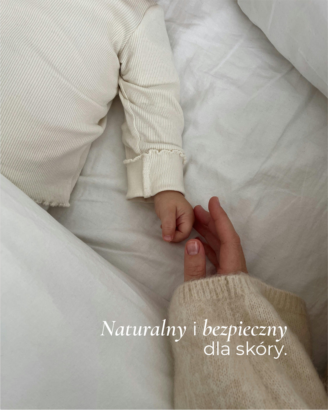 Dłoń dorosłej osoby trzyma rękę dziecka po pielęgnacji skóry naturalną glinką kaolinową Primabiotic