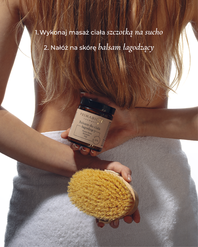 Kobieta trzyma łagodzący balsam do ciała Primabiotic i szczotkę do masażu na sucho podczas pielęgnacji skóry