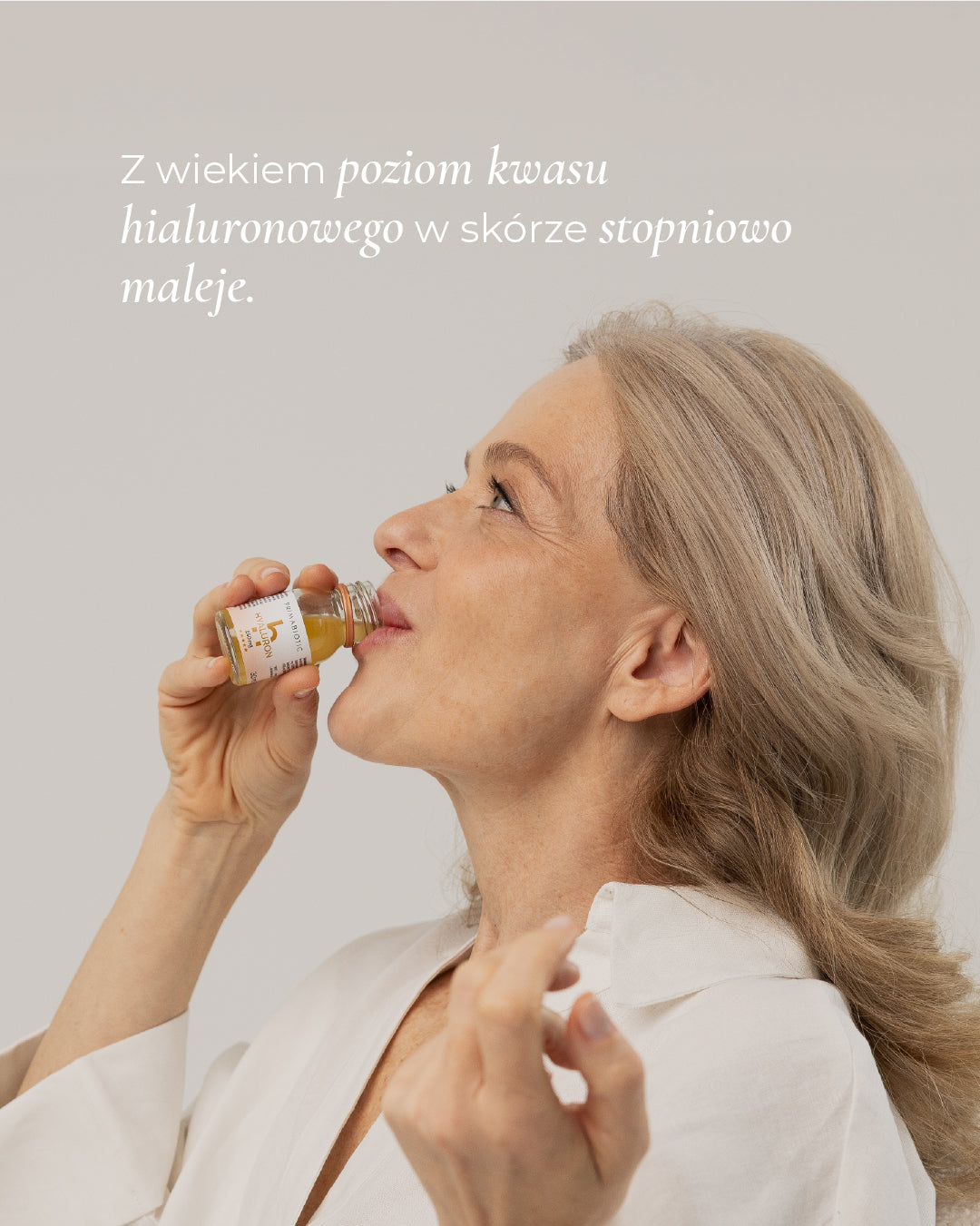 Dojrzała kobieta pije Primabiotic Hyaluron suplement z kwasem hialuronowym wspierający nawilżenie i jędrność skóry