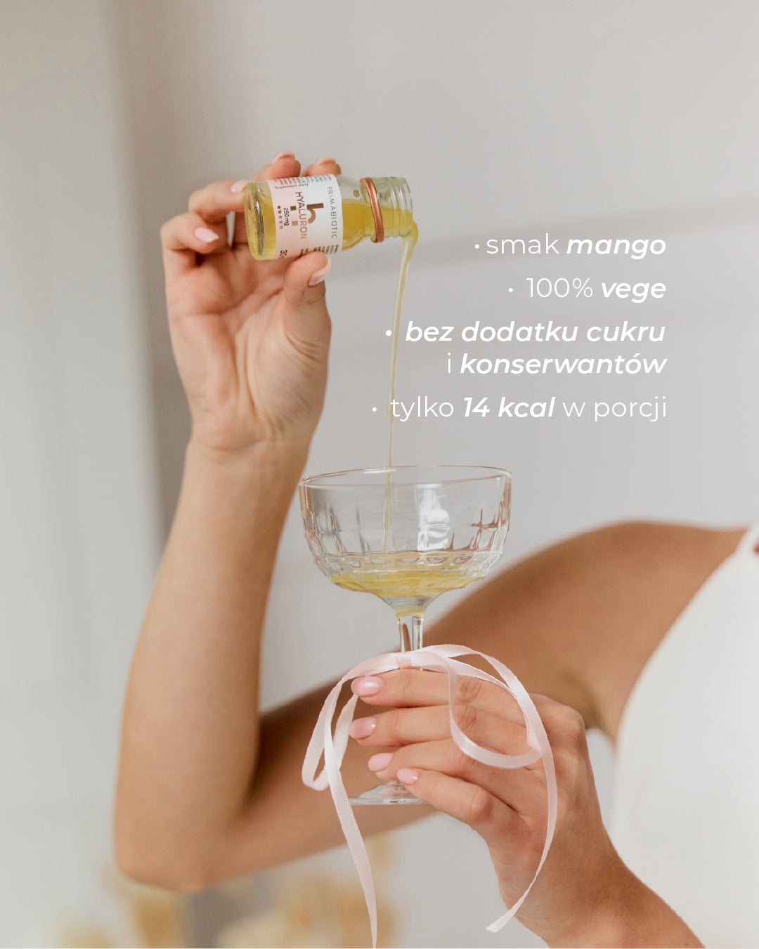 Kobieta nalewa do kieliszka Primabiotic Hyaluron wegański suplement z kwasem hialuronowym nawilżający skórę o smaku mango