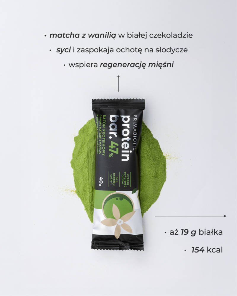 Baton proteinowy Primabiotic 47% o smaku matcha z wanilią leży na proszku matcha, zawiera 19 g białka i 154 kcal
