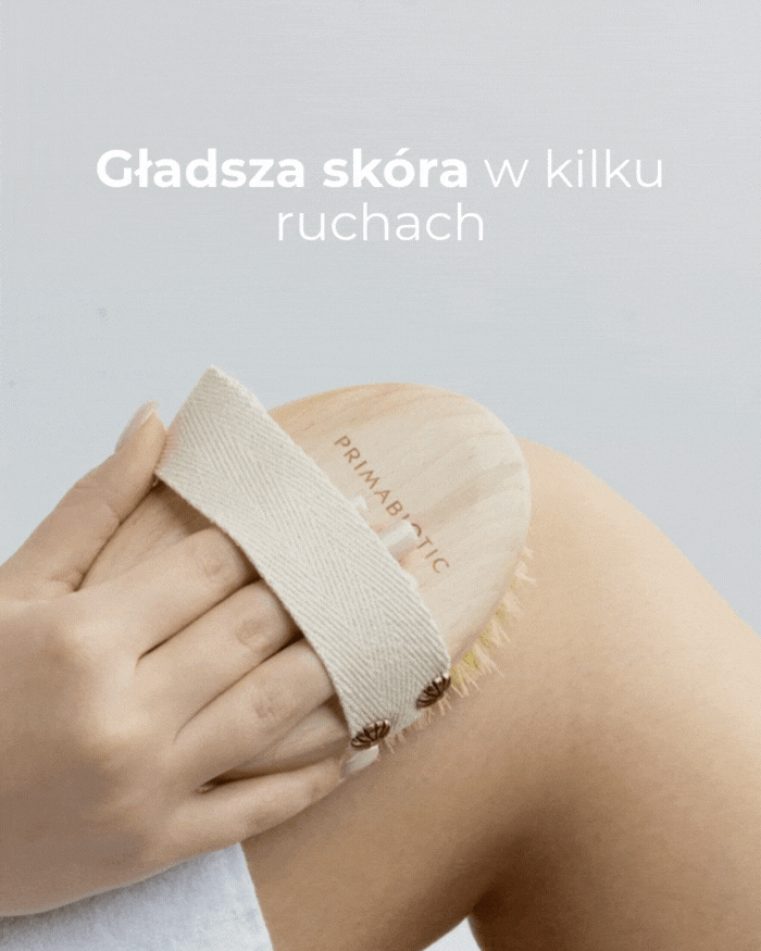 Kobieta wykonuje masaż ciała szczotką Primabiotic na udzie, wygładzając skórę