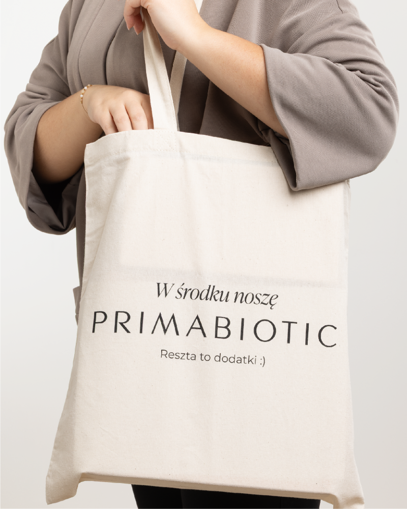 Torba bawełniana Primabiotic z napisem „W środku noszę Primabiotic” trzymana na ramieniu przez kobietę